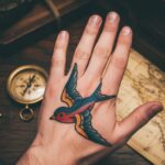 Klasyczny tatuaż jaskółki w stylu Old School na dłoni.