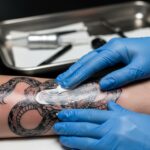 Zbliżenie na proces smarowania świeżego tatuażu kremem.