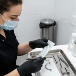 Piercerka w rękawiczkach przygotowuje sterylny pakiet z narzędziami.