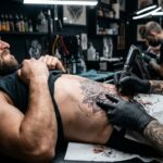 Kadr pokazujący artystę w trakcie tatuowania brzucha klienta.