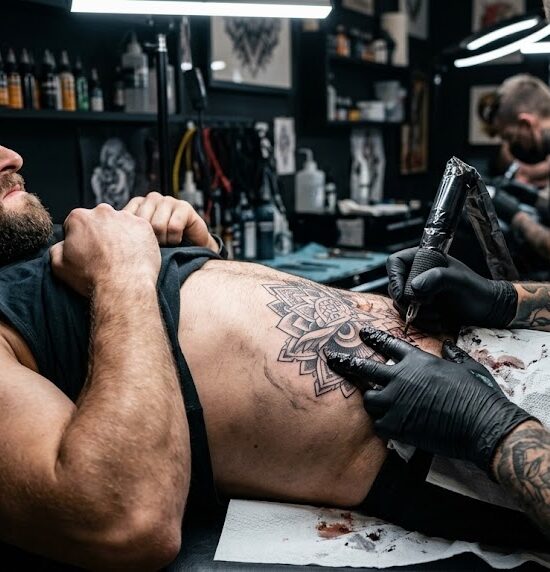 Kadr pokazujący artystę w trakcie tatuowania brzucha klienta.