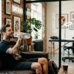 Kadr pokazujący wyluzowanego klienta siedzącego w poczekalni studia tatuażu.