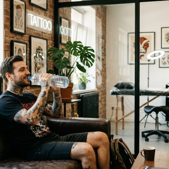 Kadr pokazujący wyluzowanego klienta siedzącego w poczekalni studia tatuażu.