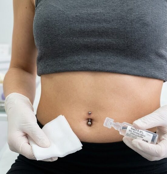Kadr przedstawiający smukły brzuch z idealnie wykonanym, świeżym przekłuciem pępka