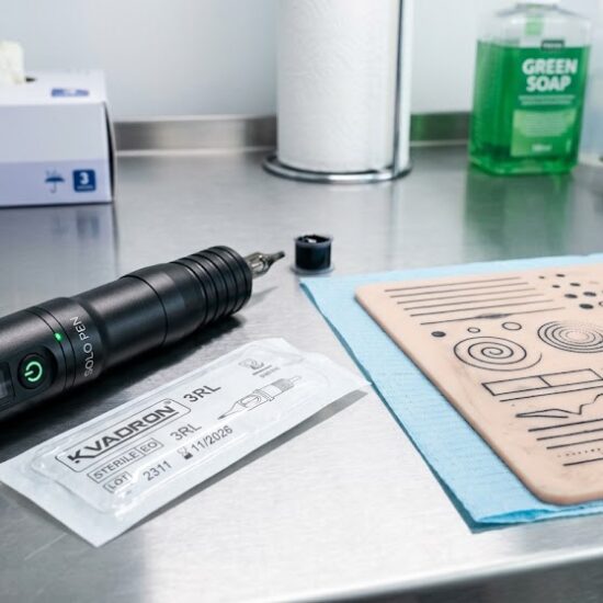 Na pierwszym planie leży nowoczesna, bezprzewodowa maszynka do tatuażu