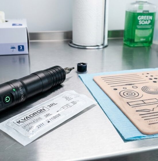 Na pierwszym planie leży nowoczesna, bezprzewodowa maszynka do tatuażu