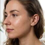 a lewym płatku nosa (przekłucie typu Nostril) widnieje minimalistyczny, tytanowy kolczyk zakończony małą cyrkonią